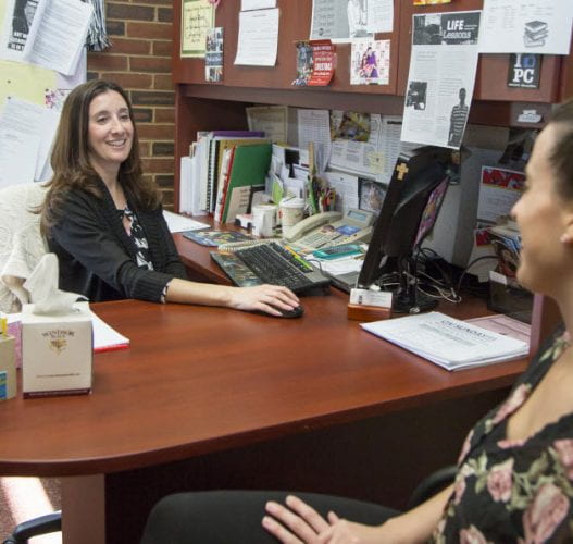 Student and staff member smiling at one another