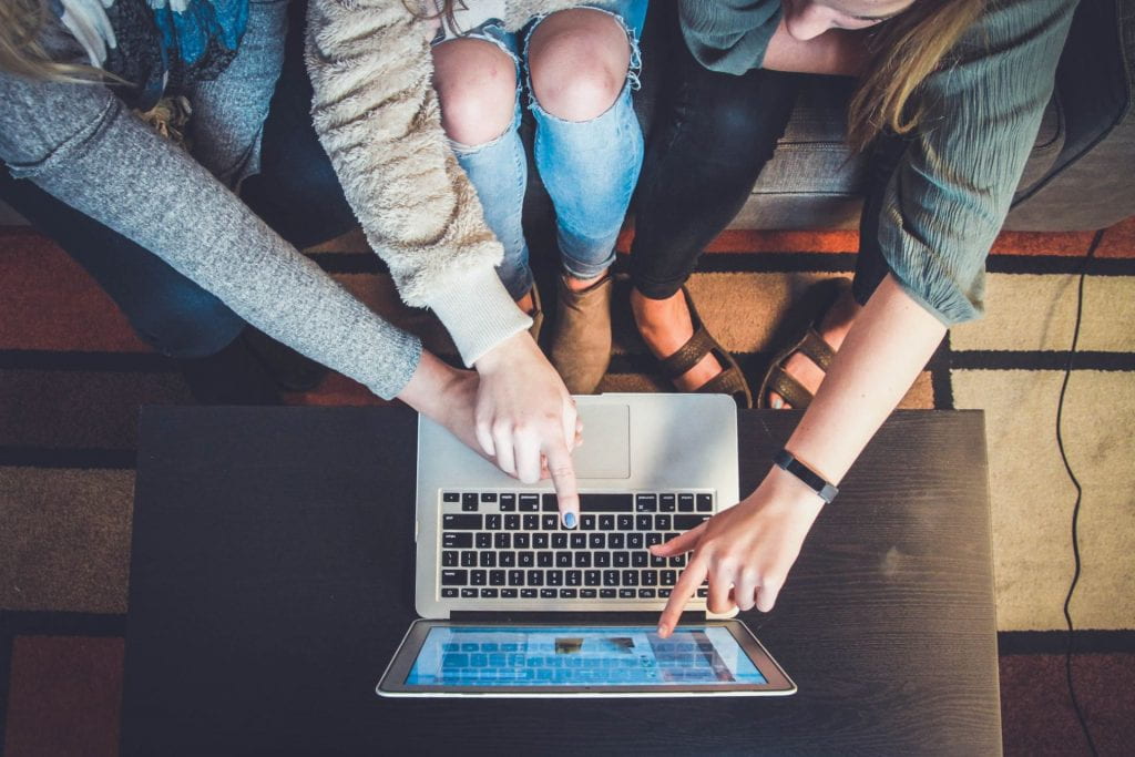 an overhead view of students looking at a laptop