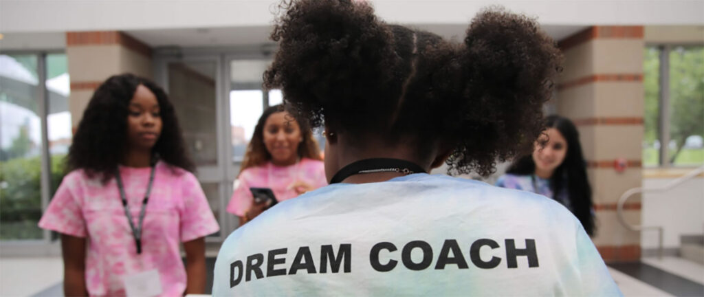 a student with a team coach shirt speaking to other students